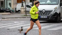 Seorang warga sedang berjoging melewati seekor bebek di Paris, Prancis (6/4/2020). Selama lockdown, orang-orang diharuskan tetap berada di rumah, kecuali untuk urusan pekerjaan, keperluan kesehatan, atau belanja kebutuhan. (Xinhua/Aurelien Morissard)