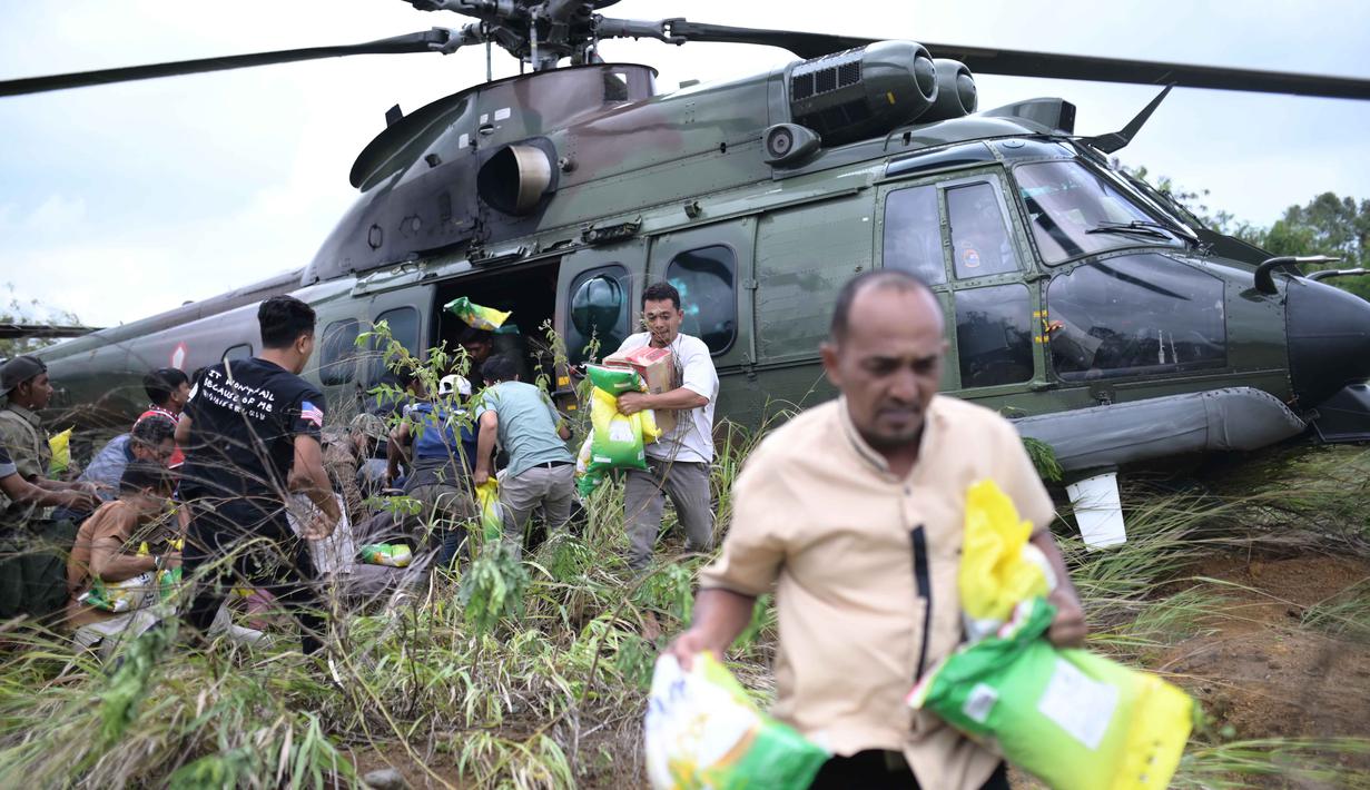 Para penyintas banjir membawa barang-barang bantuan yang didistribusikan oleh helikopter TNI AU di Aceh Tengah, Sabtu 6 Desember 2025. Meski menghadapi kendala putusnya akses darat akibat kerusakan infrastruktur parah, penyaluran bantuan banjir di Aceh Tengah terus berlangsung. (AP Photo/Reza Saifullah)