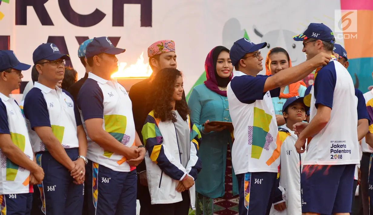 Gubernur DKI Jakarta, Anies Baswedan menyematkan medali kepada pembawa obor usai Api Obor Asian Games 2018 tiba di Balai Kota, Jakarta, Rabu (15/8). (Liputan6.com/Fery Pradolo)
