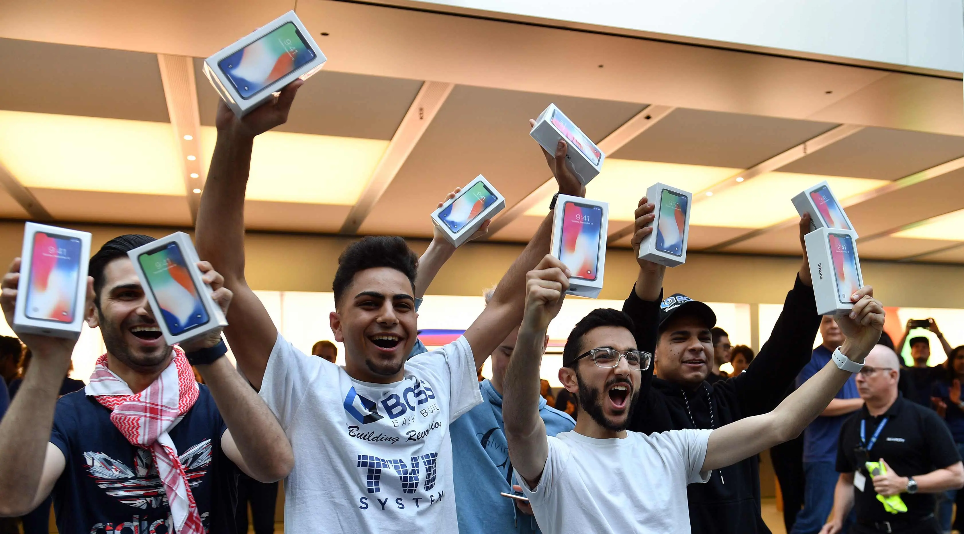 Pelanggan pertama menunjukkan iPhone X setelah ia membelinya di showroom Apple di Sydney, Australia (3/11). Apple iPhone X mulai dijual di Australia dengan antrian panjang di luar toko Apple. (AFP Photo/Saeed Khan)