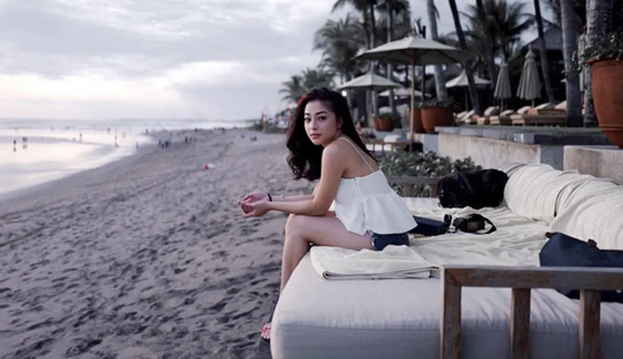 Masih di tepi pantai, Niki yang memakai atasan berwarna putih dan hot pants jeansnya terlihat duduk di pinggir  pantai. Rambutnya yang dibiarkan terurai itu begitu indah saat angin berhembus. (Instagram/nikitawillyofficial94)