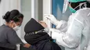 Petugas melakukan tes usap PCR kepada warga di Laboratorium Genomik Solidaritas Indonesia (GSI), Kamis (3/2/2022). Lonjakan kasus COVID-19 kembali terjadi diduga akibat varian Omicron yang mudah menular. (Liputan6.com/Faizal Fanani)