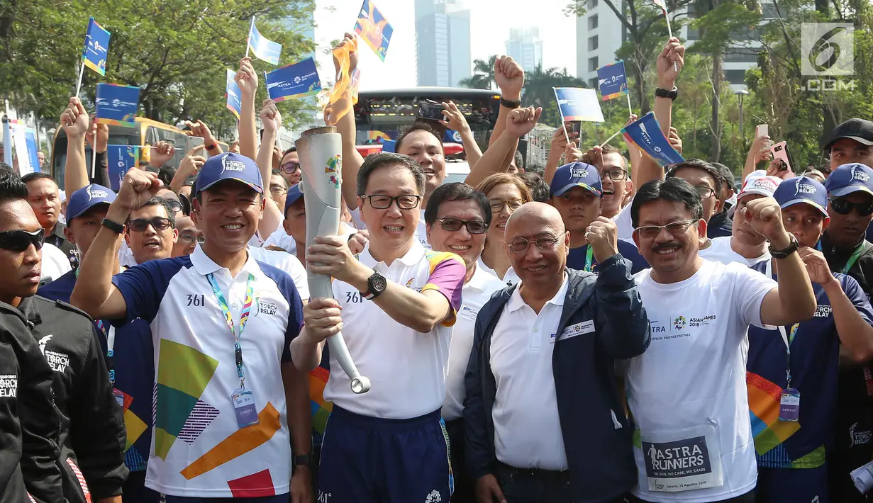 Presiden Direktur PT. Astra International Tbk, Prijono (kedua kiri) menyalakan obor saat kirab Obor Asian Games 2018 di Jalan Jendral Sudirman, Jakarta, Sabtu (18/8). (Liputan6.com/ Fery Pradolo)