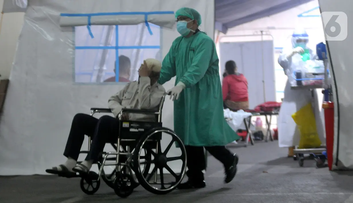 Petugas medis mendorong pasien yang duduk di kursi roda di depan UGD RSUD Cengkareng, Jakarta, Kamis (24/6/2021). Lonjakan kasus virus corona mengakibatkan ruang IGD penuh, pihak rumah sakit lantas mendirikan tenda darurat untuk merawat pasien covid-19. (merdeka.com/Arie Basuki)