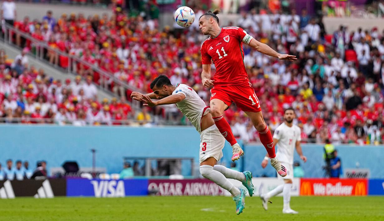 Pemain Wales Gareth Bale (kanan) melompat untuk merebut bola dengan pemain Iran Ehsan Hajsafi pada pertandingan sepak bola Grup B Piala Dunia 2022 di Stadion Ahmad Bin Ali, Al Rayyan, Qatar, Jumat (25/11/2022). Iran mengalahkan Wales dengan skor 2-0. (AP Photo/Pavel Golovkin)