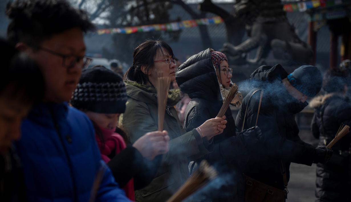 Sejumlah warga berdoa untuk keberuntungan pada hari kelima Tahun Baru Imlek di Yonghegong, atau Kuil Lama di Beijing (9/2). Warga China di seluruh dunia menyambut Tahun Babi pada 5 Februari.  (AFP Photo/Nicolas Asfouri)