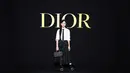 Tontawan Tantivejakul mengenakan kemeja katun putih Dior Winter 2023-2024 dengan rok kulit bordir. Dia juga mengenakan tas Dior, dasi hitam, kaus kaki, dan sepatu. [Dior]