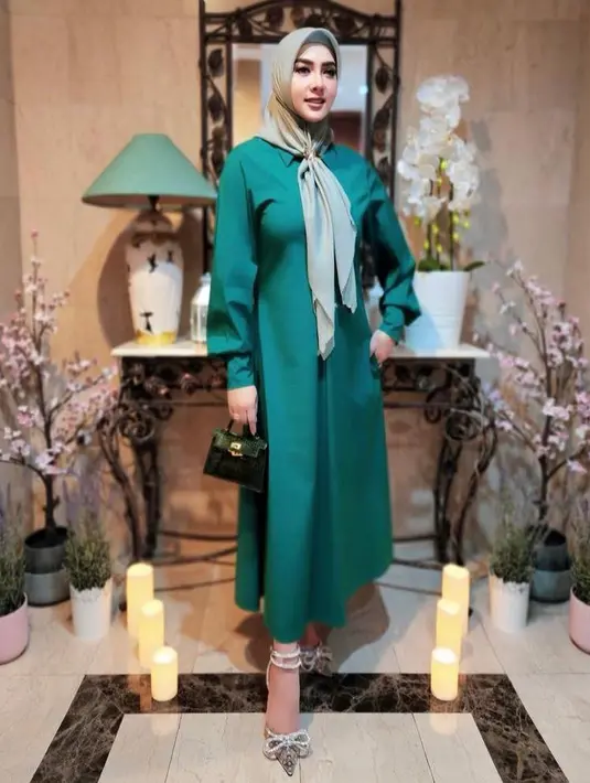 Masih menenteng tas yang sama, Syahrini mengenakan dress warna hijau yang dipadukan dengan hijab segi empat bermotif. (Instagram/princessyahrini).