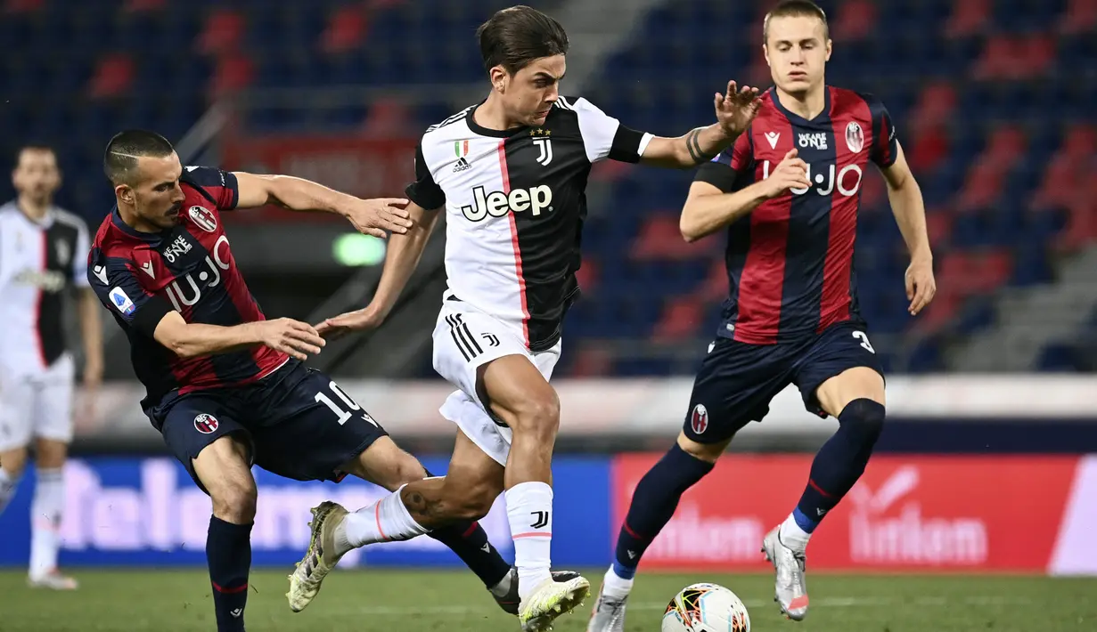 Penyerang Juventus, Paulo Dybala, berusaha melewati pemain Bologna pada laga Serie A di Stadion Renato Dall'Ara, Senin (22/6/2020). Juventus menang 2-0 atas Bologna. (AP/Massimo Paolone)