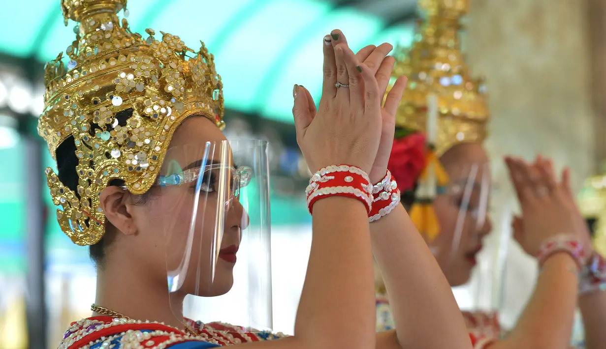 Para penari Thailand yang mengenakan pelindung wajah tampil di Kuil Erawan di Bangkok, pada 4 Mei 2020. Penampilan tari tersebut dilakukan setelah Pemerintah Thailand melonggarkan aturan pembatasan terkait penyebaran virus corona. (Xinhua/Rachen Sageamsak)