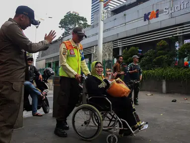 Petugas keamanan KAI Commuter Line membantu seorang calon penumpang lanjut usia (lansia) untuk masuk ke dalam Stasiun Sudirman, Jakarta, Selasa (10/12/2024). (Liputan6.com/Angga Yuniar)