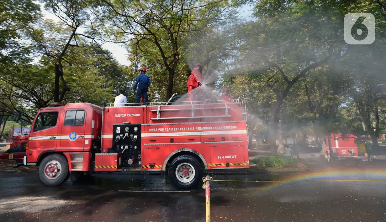 Petugas pemadam kebakaran melakukan penyemprotan cairan disinfektan tempat wisata di Taman Mini Indonesia Indah (TMII), Jakarta, Rabu (10/6/2020). Rencananya, TMII kembali dibuka untuk umum pada 20 Juni 2020 dengan menerapkan tatanan kenormalan baru. (merdeka.com/Imam Buhori)