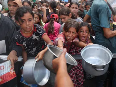 Anak-anak perempuan Palestina berkumpul untuk menerima makanan matang dari pusat distribusi makanan di kamp pengungsi Nuseirat di Jalur Gaza tengah pada 18 Agustus 2025. (Eyad BABA/AFP)