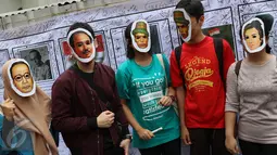 Warga berfoto bersama mengenakan topeng bergambar pahlawan nasional di depan spanduk yang penuh tanda tangan di area car free day, Jakarta, Minggu (14/5). (Liputan6.com/Immanuel Antonius)