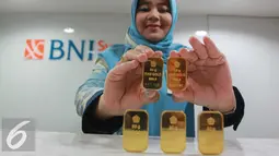 Petugas menunjukan emas batangan di Jakarta, Rabu (13/7). Harga emas batangan atau Logam Mulia milik PT Aneka Tambang Tbk (Antam) hari ini dibuka turun Rp 10.000/gram. (Liputan6.com/Angga Yuniar) 