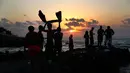 Sejumlah pemuda berdiri di atas batu karang Laut Mediterania di luar Corniche, atau promenade tepi laut, saat matahari terbenam pada hari terakhir musim panas, di Beirut, Lebanon (20/9). (AP Photo / Hussein Malla)