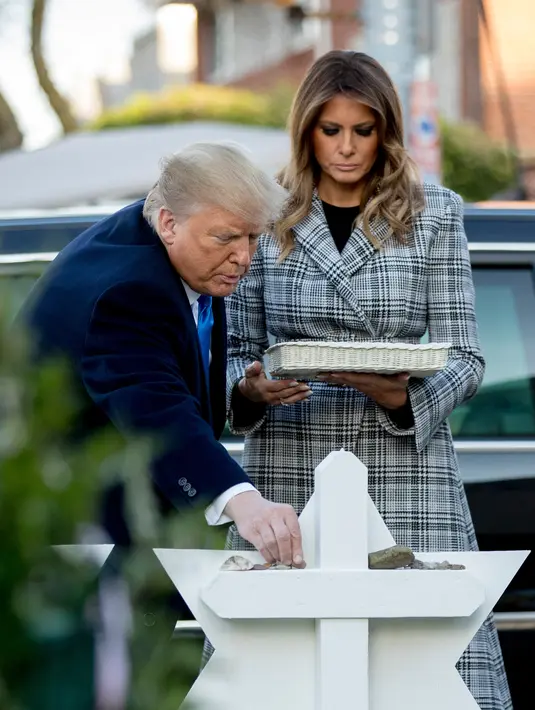 Presiden Donald Trump bersama Melania Trump meletakkan batu dari Gedung Putih di monumen peringatan penembakan maut di sinagog Tree of Life, Kota Pittsburgh, Pennsylvania, AS, Selasa (30/10). (AP Photo/Andrew Harnik)