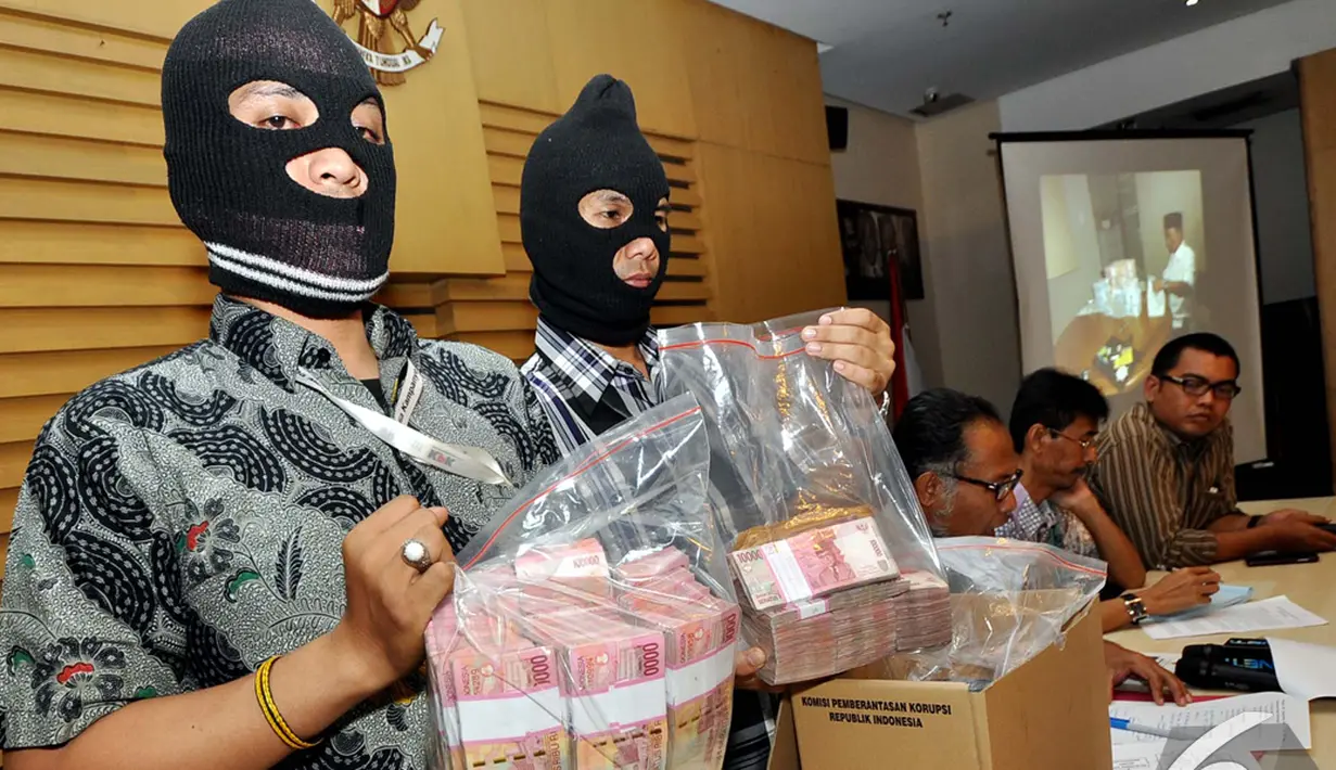 Dua penyidik KPK memperlihatkan uang pecahan Rp100 ribu dalam rilis Operasi Tangkap Tangan (OTT) Ketua DPRD Bangkalan Fuad Amin Imron di Gedung KPK, Jakarta, Selasa (2/12/2014). (Liputan6.com/Miftahul Hayat)