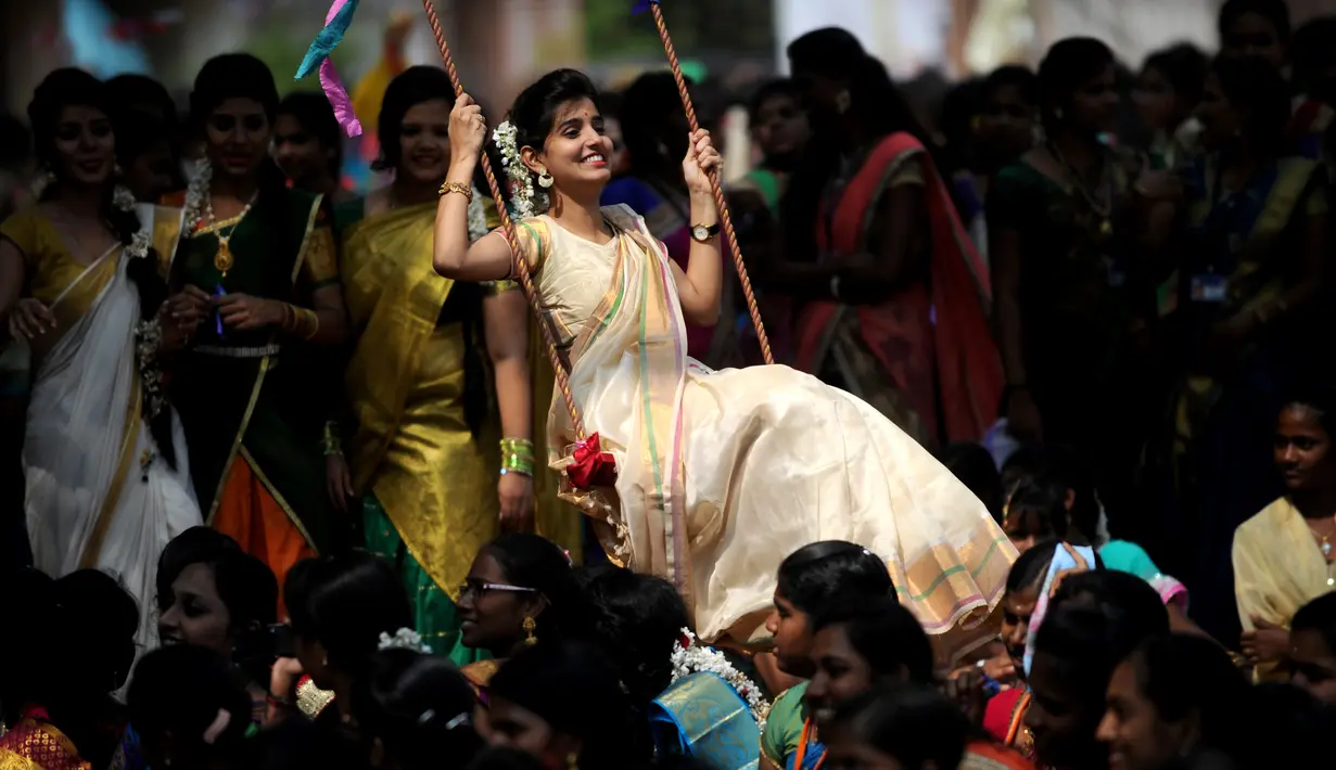 Wanita India bermain ayunan saat festival panen Tamil di perguruan tinggi di Chennai, India (11/1).  Perayaan ini sebagai simbol terima kasih warga kepada alam yang telah memberi hasil panen yang melimpah. (AFP Photo/Arun Sankar)
