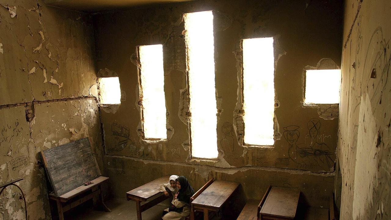 Basera, 13, kanan, dan Saira, 10, menunggu kelas mereka dimulai di sekolah Loy Ghar, di bangkai Teater Kabul yang dibom di ibukota Afghanistan, 20 April 2005 (AP Photo)