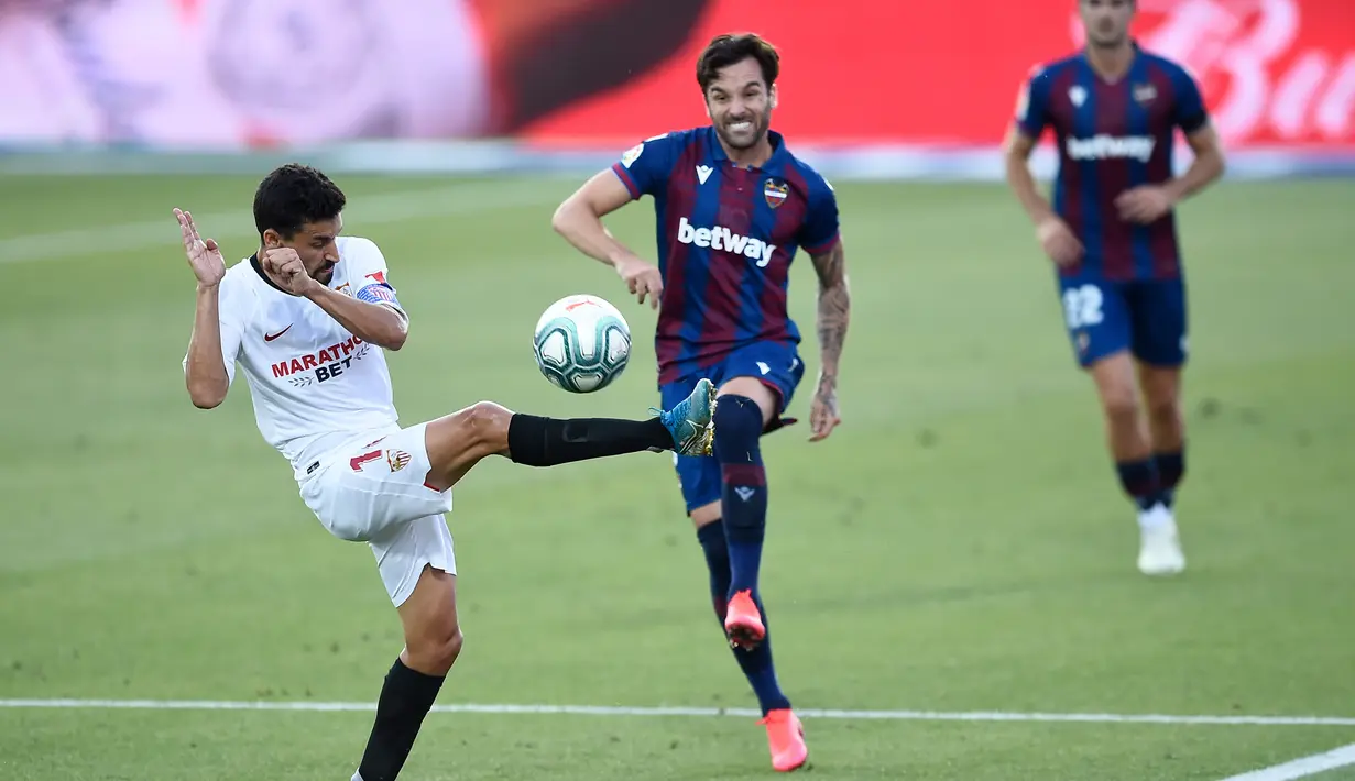 Pemain Sevilla, Jesus Navas, berusaha menghadang tendangan bek Levante, Tono, pada laga La Liga di Estadio Camilo Cano, Selasa (16/6/2020). Kedua tim bermain imbang 1-1. (AFP/Jose Jordan)