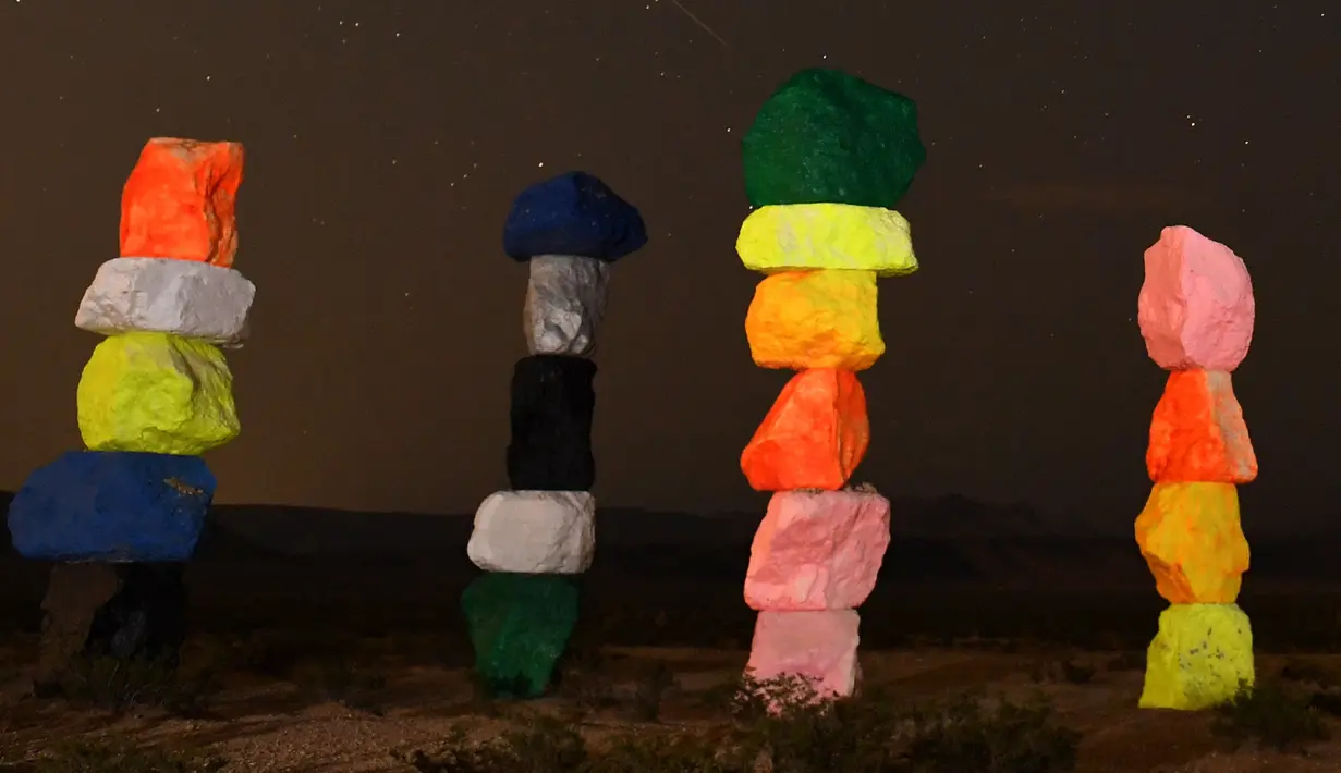 Meteor Perseid melintasi langit di atas instalasi seni "Seven Magic Mountains" dekat Jean, Nevada (13/8). Instalasi seni Seven Magic Mountains ini dibuat oleh seniman Ugo Rondinone terletak di sebelah selatan Las Vegas. (AFP Photo/Ethan Miller)