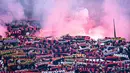 Para suporter Genoa membentangkan syal sambil menyalakan suar saat memberikan dukungan kepada timnya pada laga lanjutan Liga Italia 2023/2024 melawan Inter Milan di Stadion Luigi Ferraris, Genoa, Italia, Sabtu (30/12/2023) dini hari WIB. (AFP/Piero Cruciatti)
