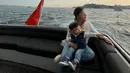 Menaiki boat, Baby Issa mengenakan long sleeve putih dan light jeans. Puffy vest navy melapisi outfit simple-nya untuk menghalau angin kencang. [@nikitawillyofficial94]