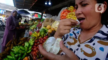 Warga mencicipi buah salju di Pasar Candi Kuning, Bedugul, Bali, Senin (24/04/2023). Buah ini sempat viral di media sosial beberapa waktu lalu. (merdeka.com/Arie Basuki)