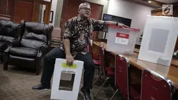 Ketua KPU Arief Budiman mencoba kekuatan menduduki kotak suara Pemilu 2019 di kantor KPU, Jakarta, Kamis (16/11). Arief menyebut biaya yang akan dikeluarkan diprediksi lebih sedikit dibanding kotak suara berbahan plastik. (Liputan6.com/Faizal Fanani)