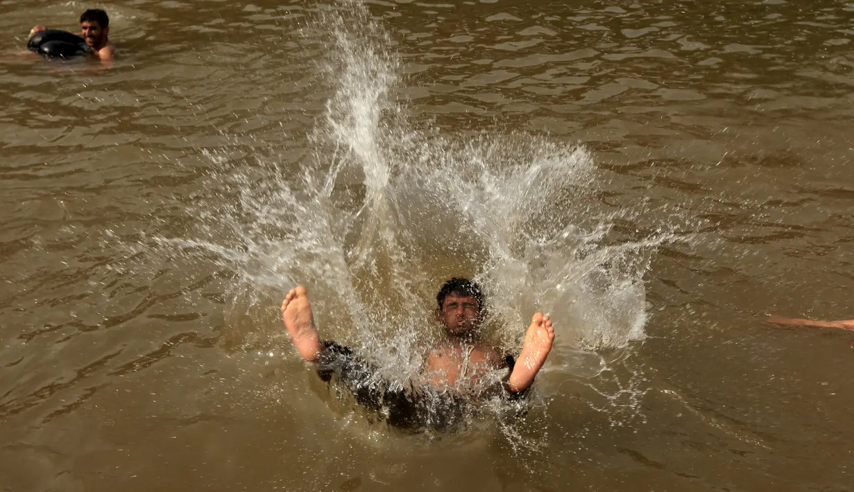 Seorang pria melompat ke sungai untuk mendinginkan tubuhnya saat cuaca panas yang ekstrem di Islamabad, Pakistan, (23/6/2015). Gelombang panas membuat warga Pakistan tak bisa jauh dari air untuk bertahan hidup. (REUTERS/Faisal Mahmood)