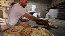 Pekerja membuat somun di sebuah toko roti di kota tua Sarajevo, Bosnia and Herzegovina, Kamis (30/4/2020). Roti somun lebih nikmat disantap selagi hangat saat berbuka puasa atau sahur. (ELVIS BARUKCIC/AFP)