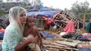 Pengungsi Rohingya duduk di dekat rumahnya setelah Topan Mora menghantam di sebuah kamp di distrik Cox's Bazar, Bangladesh (31/5). Ribuan rumah dan tenda-tenda yang beratap jerami di kamp tersebut hancur akibat Topan Mora. (AFP Photo/Str)