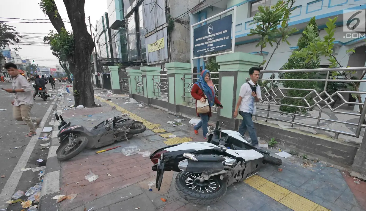 Pejalan kaki melintas di dekat dua motor yang rusak pascakerusuhan di sekitaran Jakarta, Kamis (23/5/2019). Aksi unjuk rasa itu dilakukan menyikapi putusan hasil rekapitulasi nasional Pemilu serentak 2019. (Liputan6.com/Herman Zakharia)
