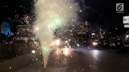 Warga menyalakan kembang api di tengah pawai untuk memeriahkan malam takbiran di sepanjang Jalan Mas Mansyur, Tanah Abang, Jakarta Pusat, Kamis (14/6) malam. (Liputan6.com/Johan Tallo)