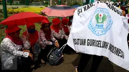 Sejumlah guru berteduh saat mengelar unjuk rasa di Gedung DPR/MPR, Jakarta, Kamis (12/1). Dalam aksinya mereka menuntut kenaikan upah dan mendesak pemerintah kususnya DPR agar tidak melakukan diskriminasi terhadap guru swasta. (Liputan6.com/Johan Tallo)