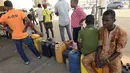 Warga Nigeria duduk di atas jerigen saat antre mengisi bahan bakar di sebuah SPBU di Lagos, Selasa (1/12). Krisis bahan bakar yang telah melanda Nigeria dalam beberapa bulan terakhir menyebabkan antrean panjang di SPBU. (AFP PHOTO/PIUS Utomi EKPEI)
