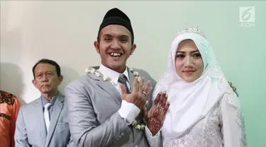 Komedian Caisar Aditya Putra dan Intan Sri Mardiani menunjukkan cincin usai ijab kabul pernikahan di kawasan Cimahpar, Bogor, Jawa Barat, Sabtu (30/6). Caisar resmi menikahi Intan usai bercerai dari Indadari. (Liputan6.com/Herman Zakharia)