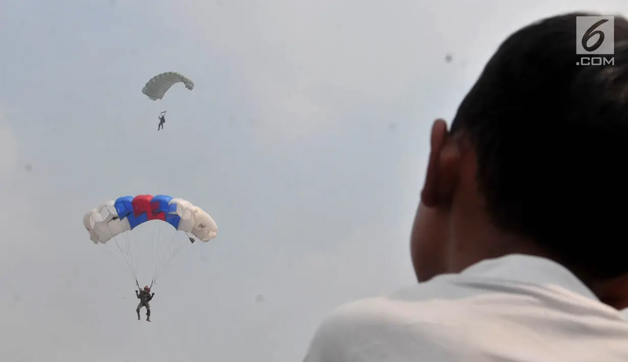 Warga menyaksikan aksi terjun payung saat Festival Damai Millenial Road Safety di Monas, Jakarta, Minggu (23/6/2019). Aksi ini diikuti puluhan penerjun payung dari personel gabungan TNI-Polri. (merdeka.com/Iqbal Nugroho)