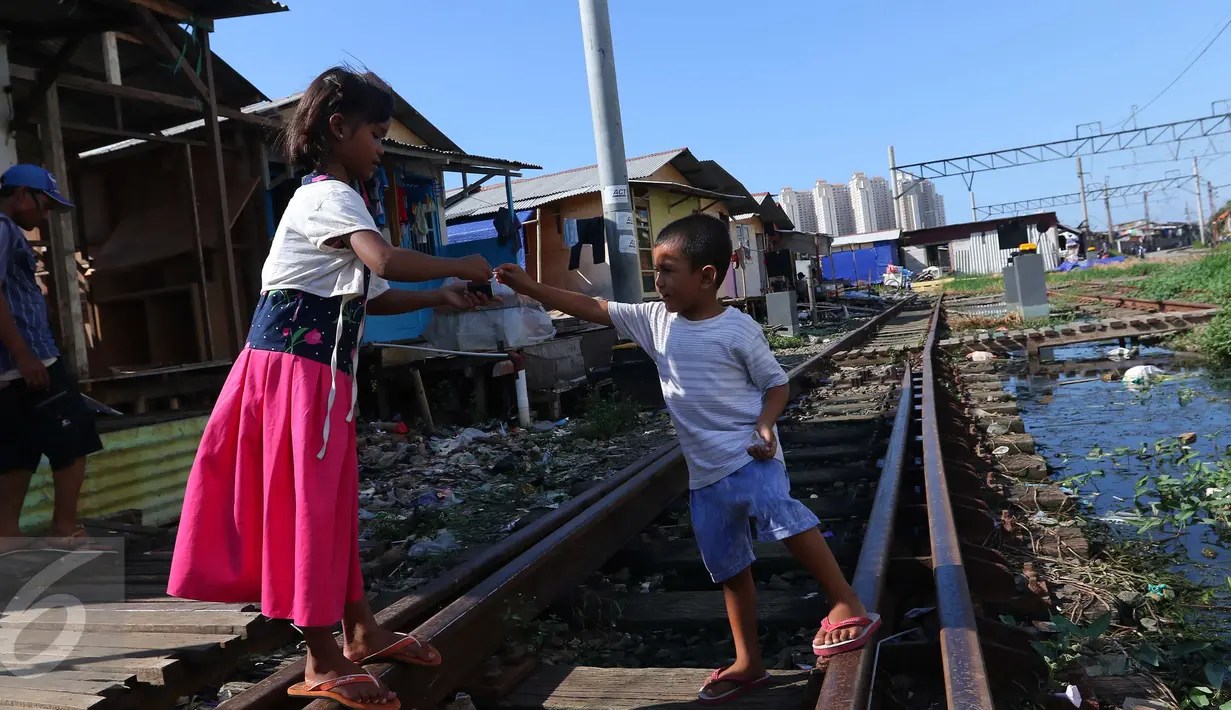 Anak-anak bermain di jalur kereta api di premukiman kampung bandan, Jakarta, Jumat (15/7). Nantinya masing-masing US$ 216,5 juta atau sekitar 2,8 triliun rupiah untuk perbaikan infrastruktur permukiman kumuh di Indonesia. (Liputan6.com/Angga Yuniar)