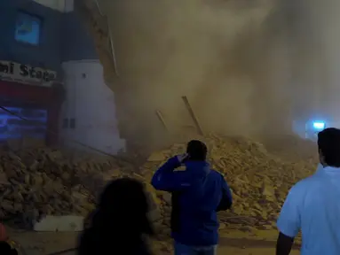 Sejumlah orang menyaksikan puing gedung bioskop tua yang tengah direnovasi sesaat setelah runtuh di Tucuman, Argentina, Rabu (23/5).Sedikitnya satu orang tewas akibat kejadian tersebut. (AFP PHOTO/Walter Monteros)