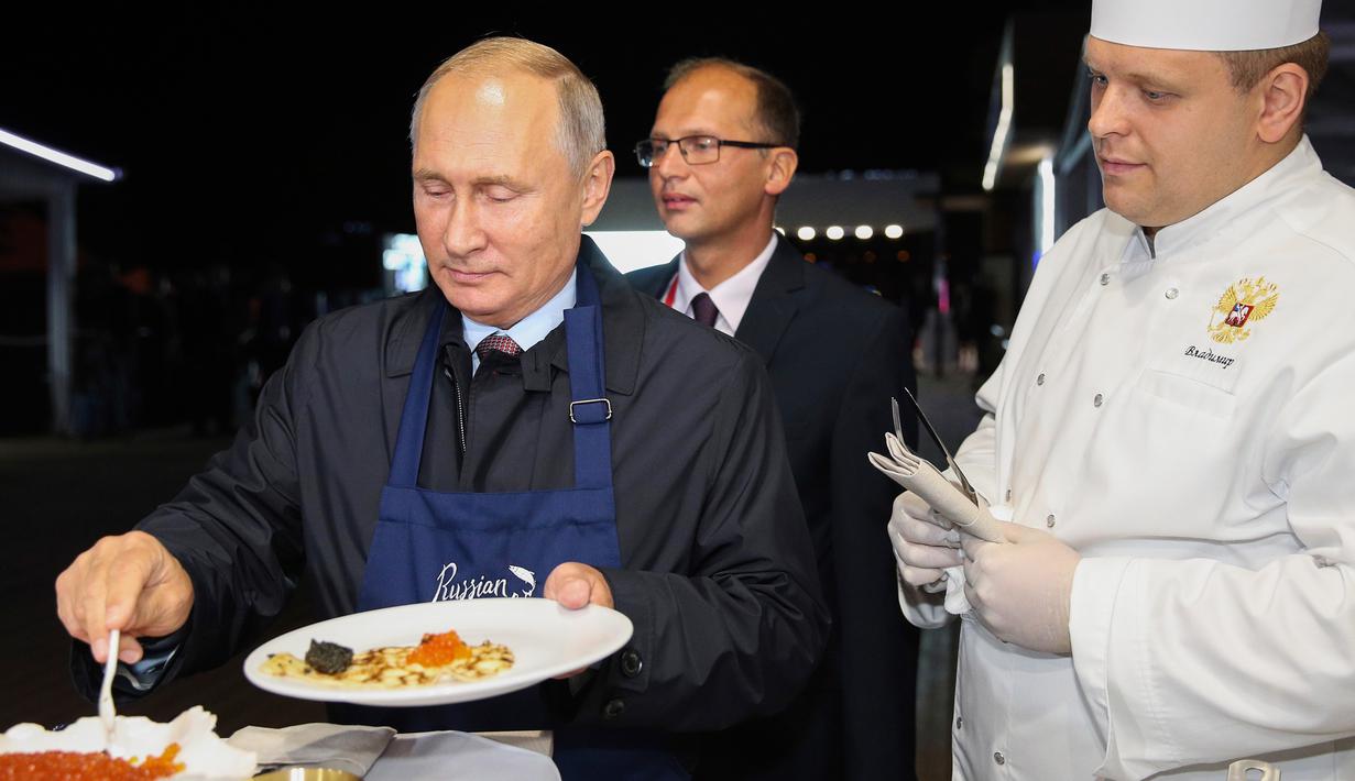 Presiden Rusia Vladimir Putin (kiri) menyantap pancake buatannya bersama Presiden China Xi Jinping di sela acara Eastern Economic Forum di Vladivostok, Rusia, Selasa (11/9). (Sergei Bobylev/TASS News Agency Pool Photo via AP)