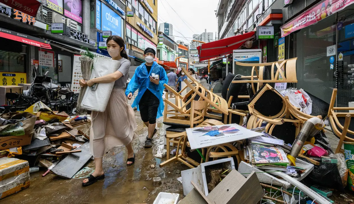 Pejalan kaki berjalan melewati puing-puing di luar toko-toko di Pasar Namseong yang bersejarah di distrik Gangnam Seoul (9/8/2022). Presiden Korea Selatan meminta agar jajarannya siap untuk melawan dampak lebih lanjut dari banjir di wilayah Seoul dan sekitarnya, seperti tanah longsor.
