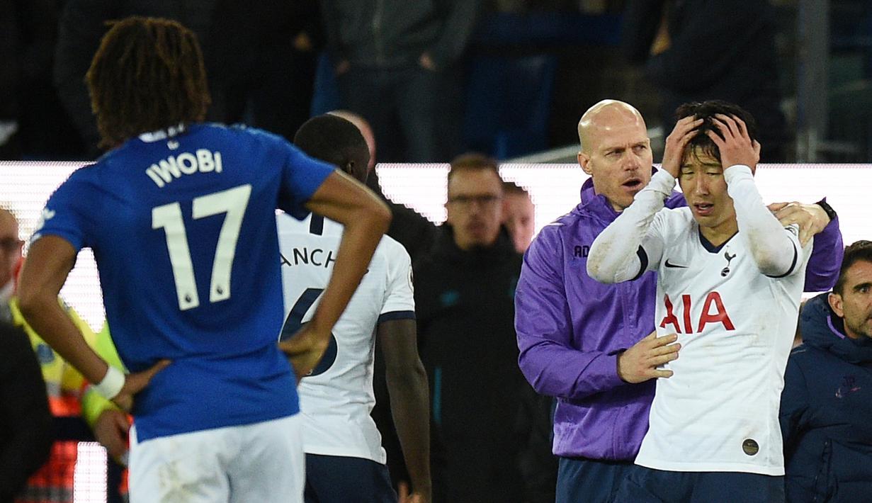 Penyerang Tottenham Hotspur, Son Heung-min, tampak menyesal usai melakukan pelanggaran terhadap gelandang Everton, Andre Gomes, pada laga Premier League di Goodison Park, Minggu (3/11). Tekel tersebut menyebabkan Gomes mengalami patah kaki. (AFP/Oli Scarff)