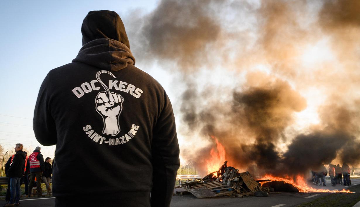 Kepulan asap hitam mewarnai aksi yang dijalankan puluhan anggota serikat pekerja Konfederasi Umum Buruh Prancis (CGT) untuk menentang perombakan dana pensiun yang sangat tidak populer di Donges, Prancis Barat, Rabu (8/2/2023). Prancis bersiap menghadapi pemogokan baru dan demonstrasi massal menentang proposal Presiden Prancis untuk mereformasi pensiun Prancis, termasuk menaikkan usia pensiun dari 62 menjadi 64 tahun. (LOIC VENANCE/AFP)