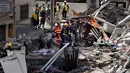 Petugas pemadam kebakaran dikerahkan ke lokasi runtuhnya gedung apartemen lima lantai di kota wisata Los Cristianos, Tenerife, Spanyol, Kamis (14/4). Tim penyelamat dibantu anjing pelacak terus berusaha mencari para korban. (Desiree MARTIN/AFP)