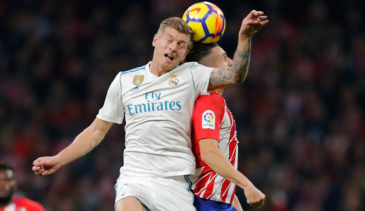 Pemain Real Madrid, Toni Kroos dan pemain Atletico Madrid, Saul Niguez berebut bola pada pertandingan pekan ke-12 Divisi Primera La Liga Spanyol di Stadion Wanda Metropolitano, Sabtu (18/11). Laga Derbi Madrid itu berakhir imbang tanpa gol (AP/Paul White)