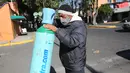 Omar Ramirez membawa tangki oksigen yang telah diisi ulang untuk keluarganya yang sakit COVID-19 di Mexico City, 27 Desember 2020. Lonjakan pasien terinfeksi virus corona yang dirawat di Mexico City membuat toko pasokan medis kekurangan pasokan isi ulang tabung oksigen. (AP Photo/Ginnette Riquelme)