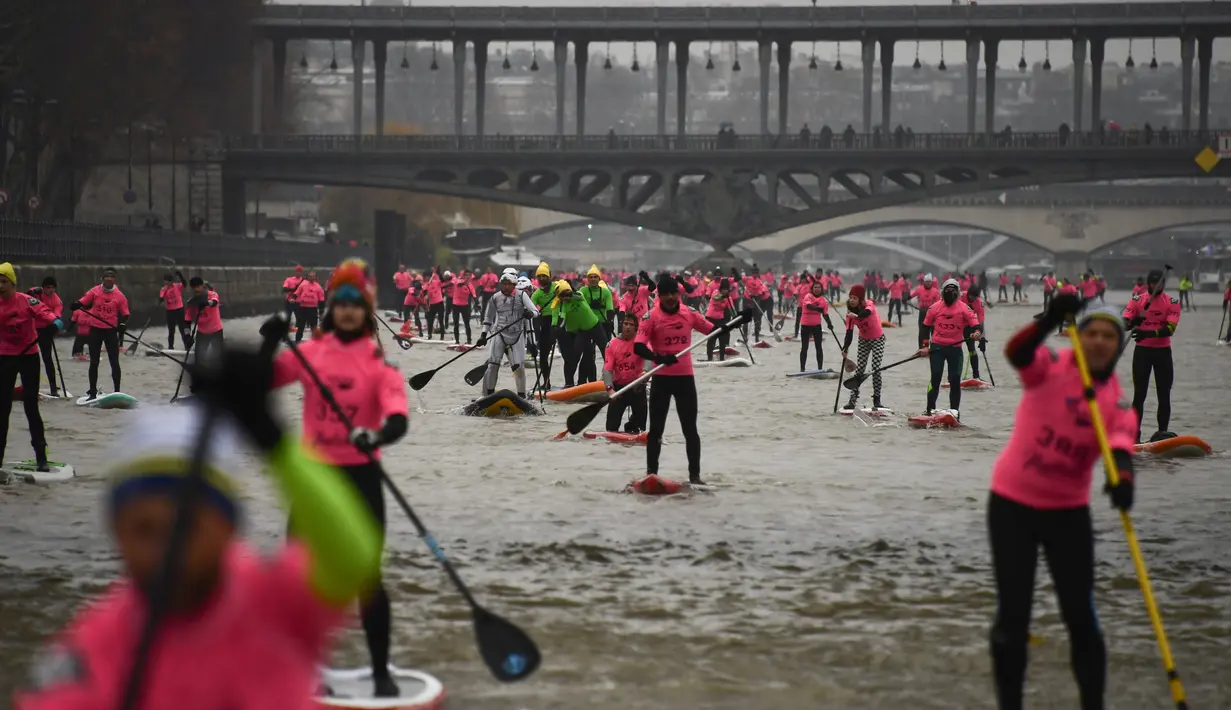 Para peserta ambil bagian dalam perlombaan dayung sambil berdiri pada Nautic SUP Paris di sepanjang sungai Seine, Paris, Minggu (3/12). Sekitar 700 peserta berpartisipasi menyeberangi sungai Seine dengan pemandangan kota Paris (AFP PHOTO/CHRISTOPHE SIMON)
