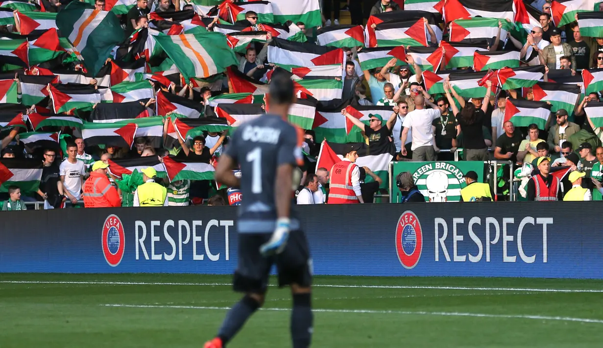 Bendera Palestina dikibarkan oleh suporter Celtic saat melawan Hapoel Beer Sheva di kualifikasi Liga Champions di Celtic park, (19/8).  Aksi dilakukan sebagai bentuk kecaman terhadap invasi Israel yang terjajah hingga saat ini. (REUTERS/Russell Cheyne)
